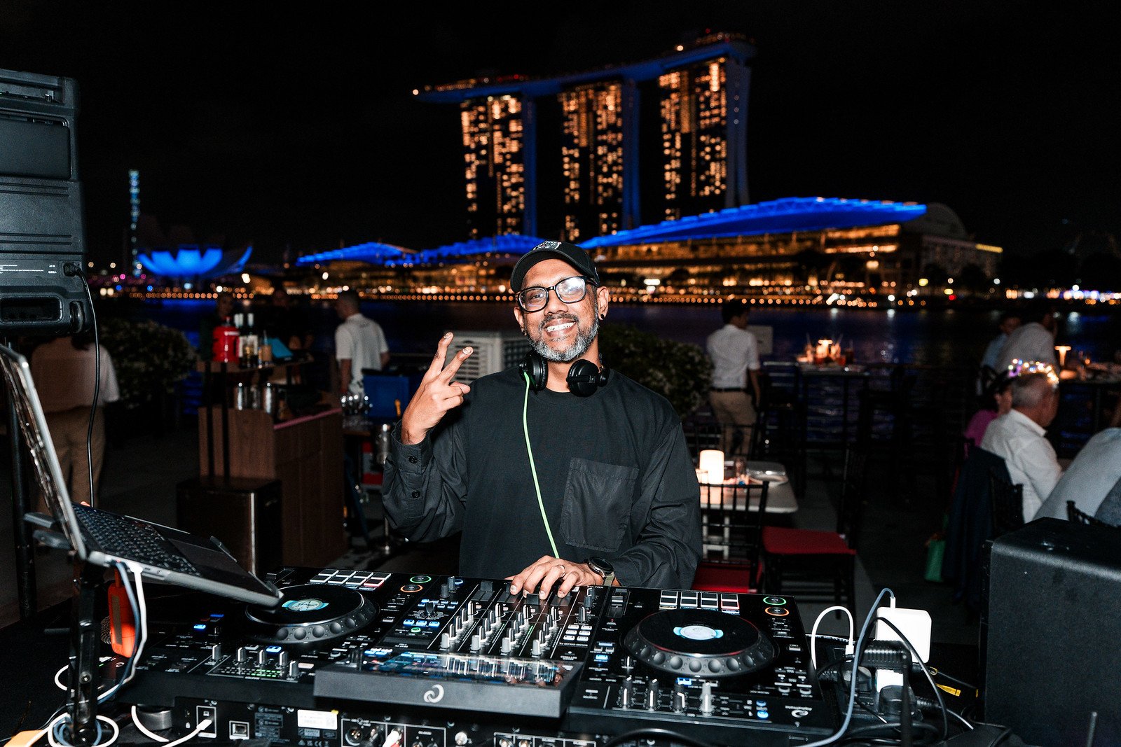 DJ performing at a waterfront event with Marina Bay Sands behind
