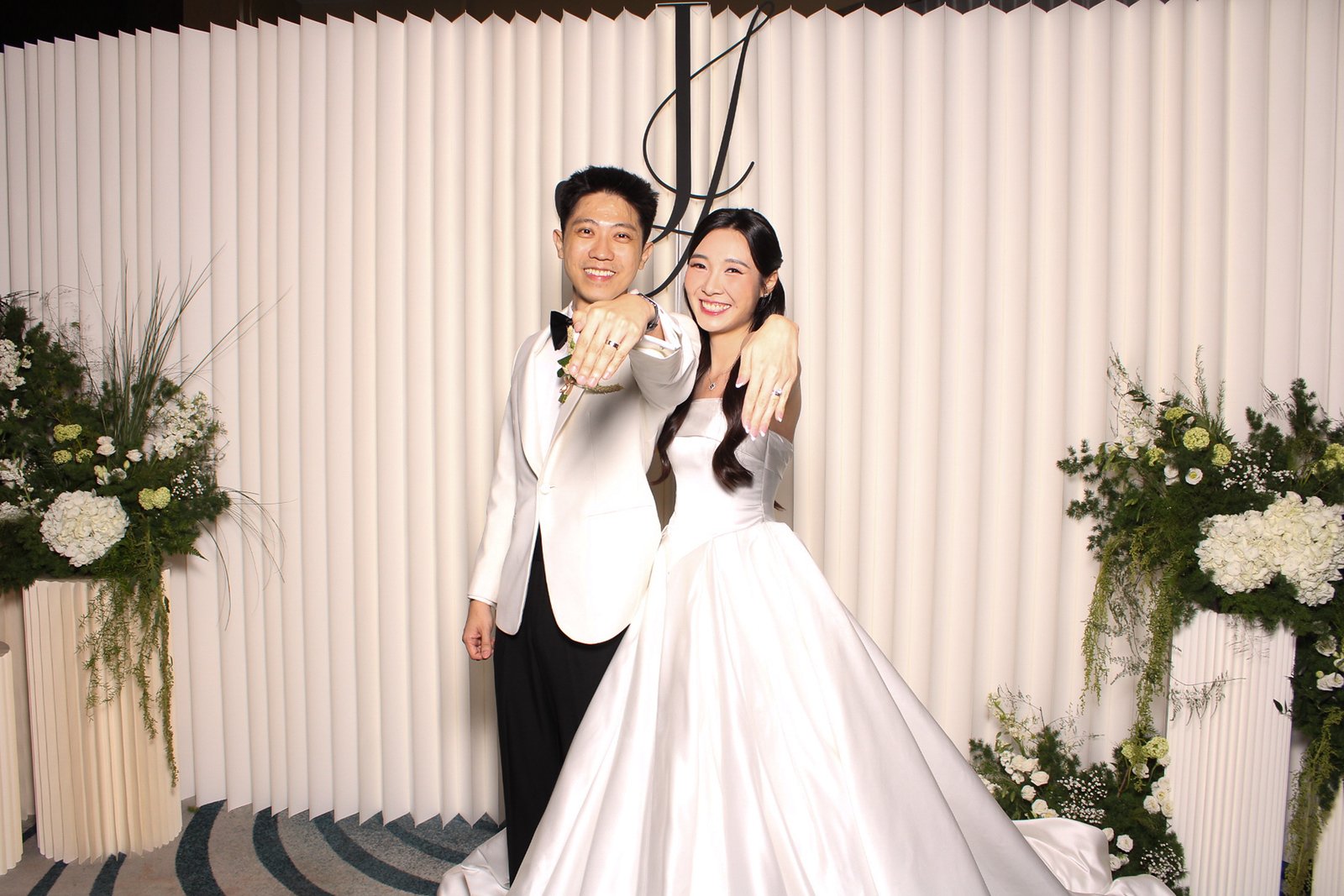 Newlyweds showing their rings at an elegant wedding photobooth