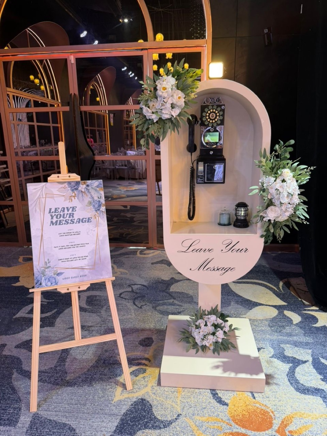 Guests recording a message at a ShutterPop video guest book with decorated backdrop